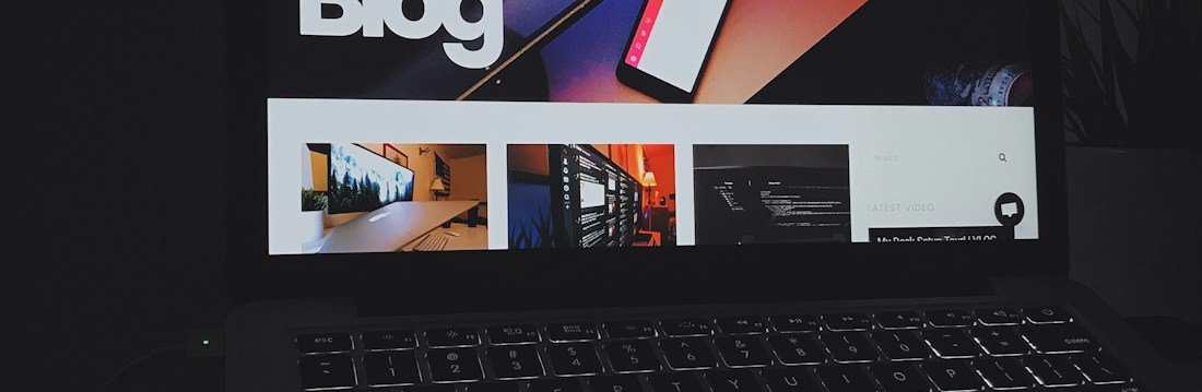 A laptop showing a blog home page, its headline above a row of article thumbnails.