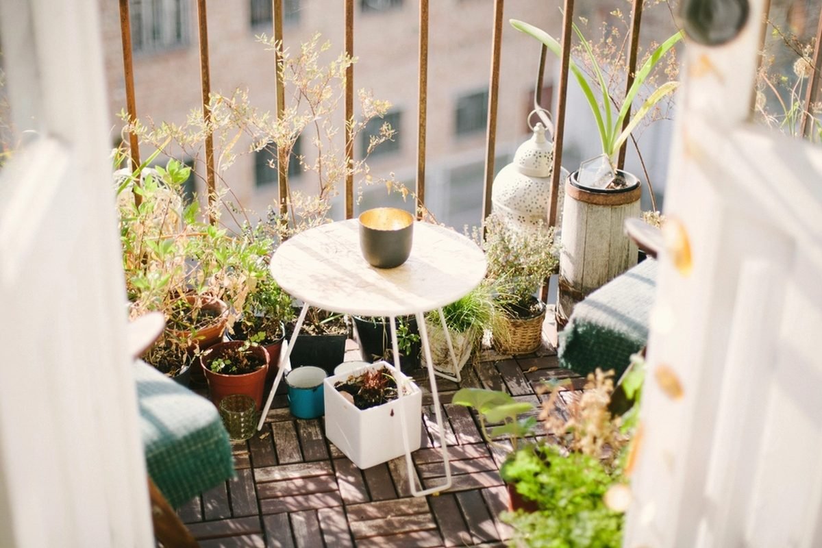 A small balcony crowded with potted plants around a round table.