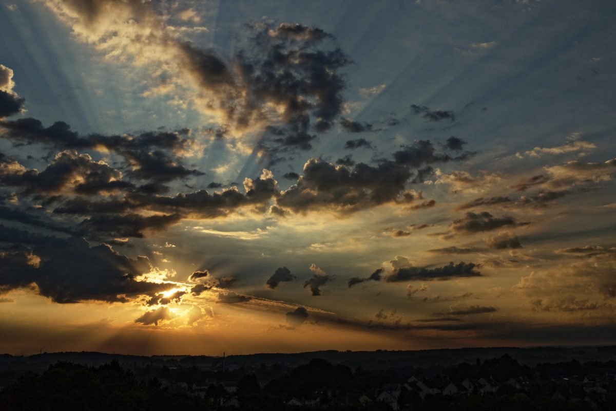 Sunrise breaking through heavy cloud over a dark horizon.