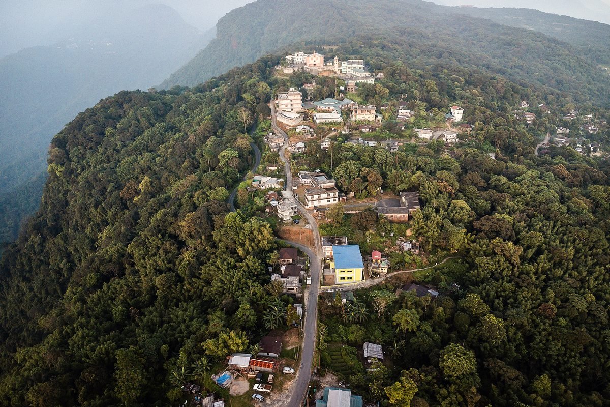 A village on a forested hillside under low cloud.