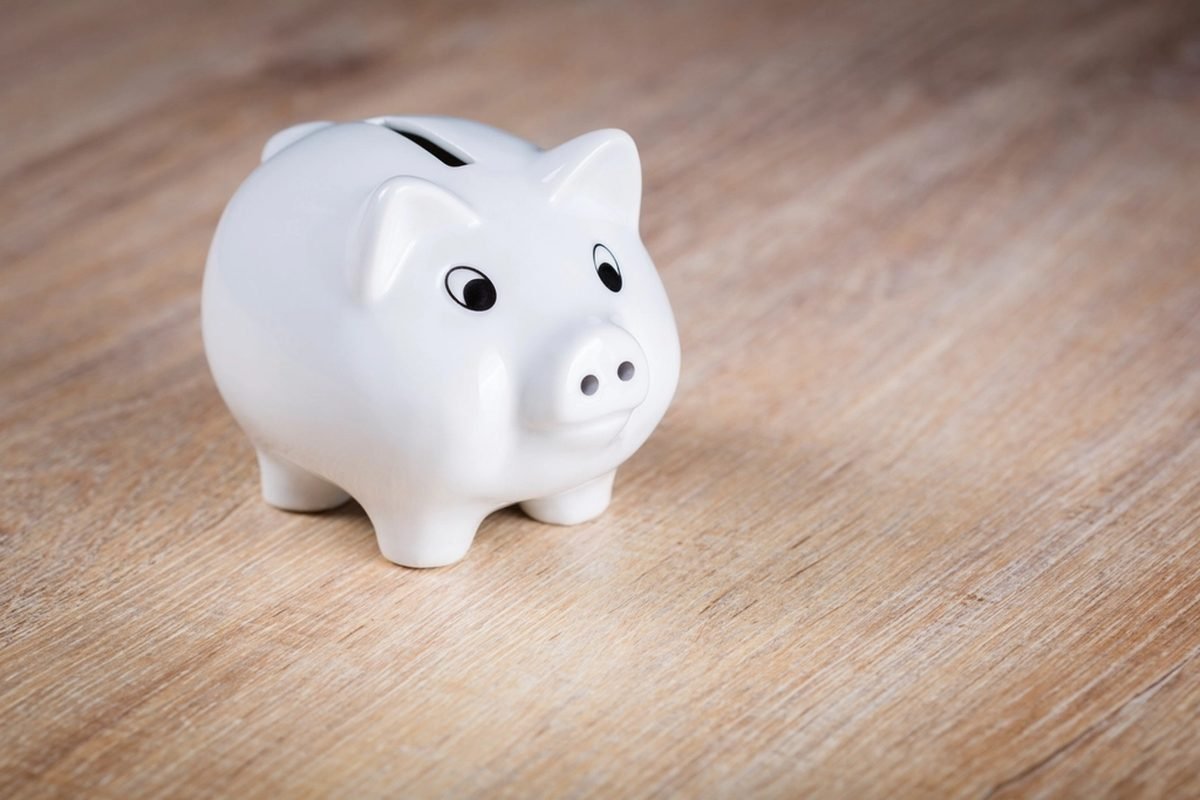 A white ceramic piggy bank on a wooden table.