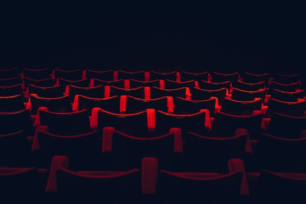 Rows of empty cinema seats lit red in the dark.